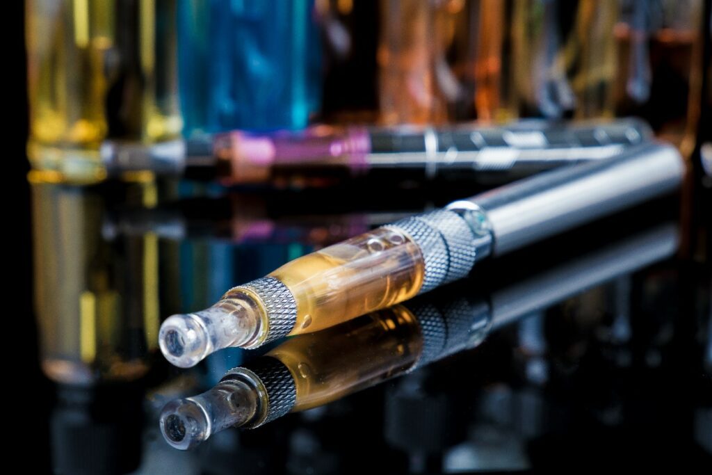 E-Zigarette mit Liquid-Fläschchen im Hintergrund